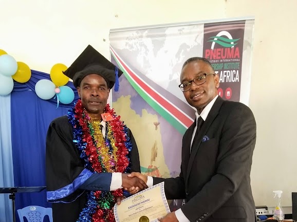 Reggie Holiday presenting a certificate to a Pneuma Leadership Institute graduate in Nairobi, Kenya.