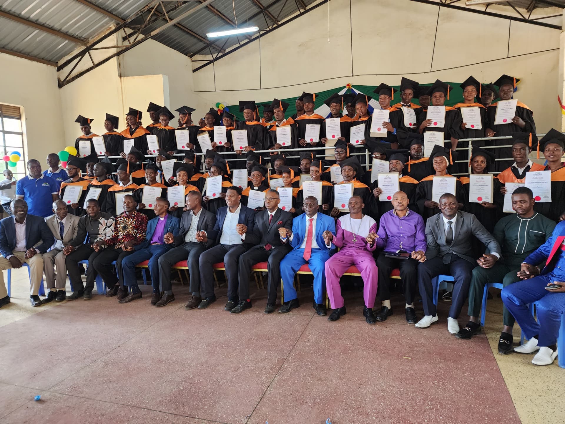 A large Pneuma Ministries International leadership certification graduating class holding certificates.