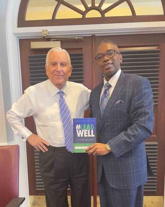 Reggie Holiday presenting a copy of #LeadWell to a university president.