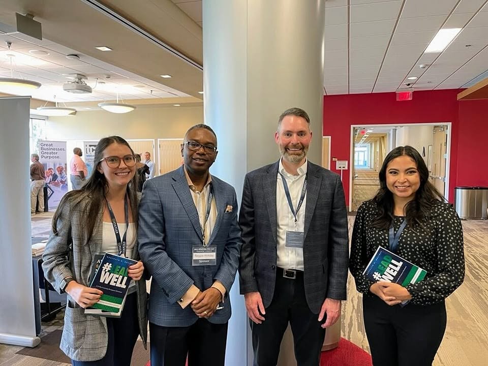 Reggie Holiday with business leaders holding copies of #LeadWell at a regional pro day event.